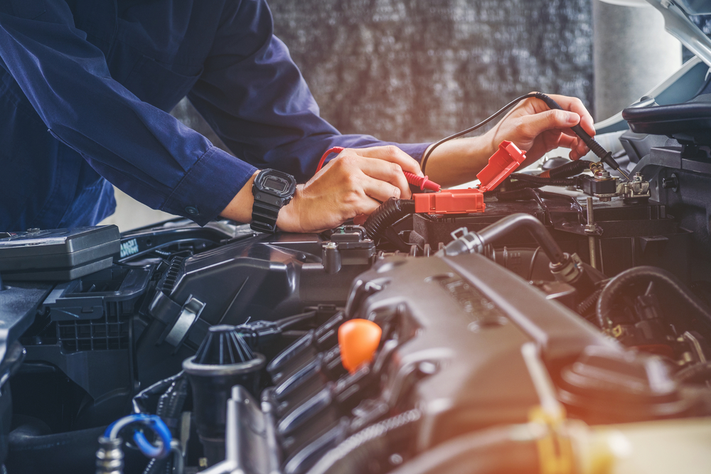 Mechanic inspecting a vehicle's engine bay prior to a road trip.