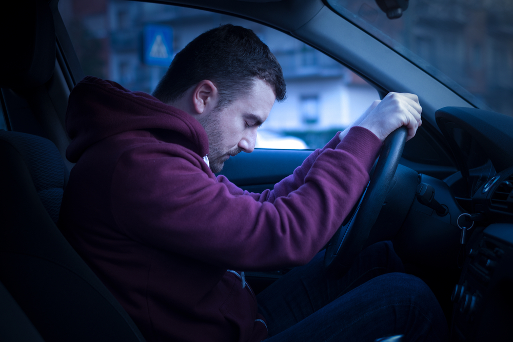 A tired driver with closed eyes demonstrating why you should not drive while tired.