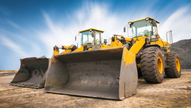 Two yellow heavy-duty bulldozers standing on a building site