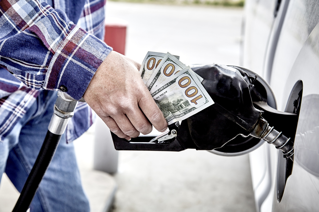 Mans hand holding cash while refueling vehicle