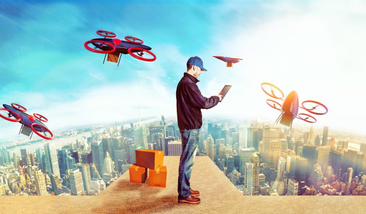 Delivery man stands on top of a building with a digital tablet to control and survey the dornes. Concept of a future smart city with mail delivery by drones.