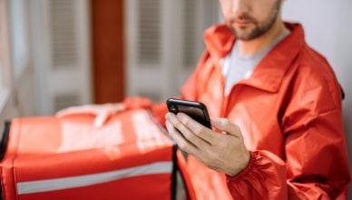 Food delivery man checking the best route planner app for delivery drivers for routes