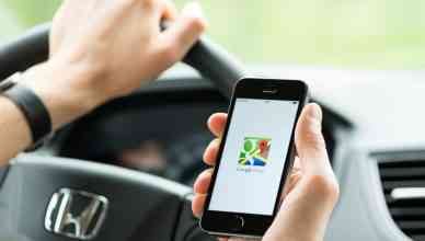 Man in the car planning a route using a Google Maps route planner app on Apple iPhone 5S. Google Maps is a most popular web mapping service for mobile provided by Google inc.