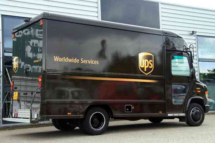 UPS delivery Truck parked by the side of the road in front of a office building. An example of how UPS route optimization software works.