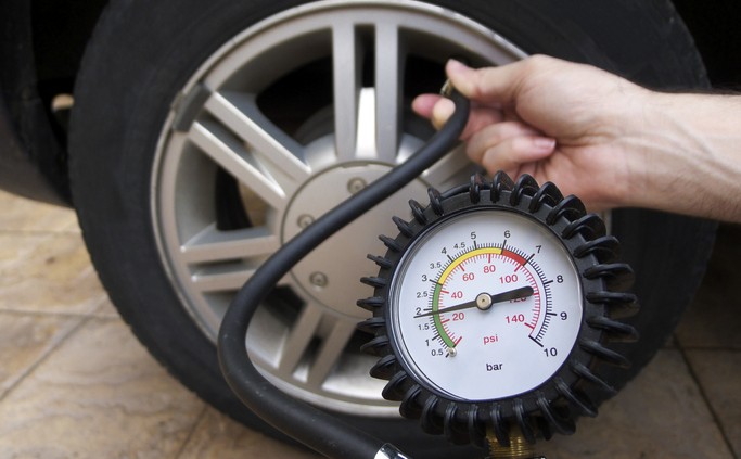 Close-up of manometer and man hands checking tire pressure with gauge.