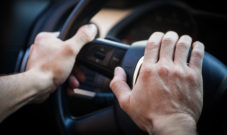 Image of a hand honking the horn inside a car.