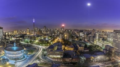 Johannesburg cityscape and moonlight, taken at sunset, showing the illuminated Council Chamber which is set to be the centre for the revitalisation and urban renewal of the precinct. Hillbrow residential area and the prominent communications tower and Ponte flats.